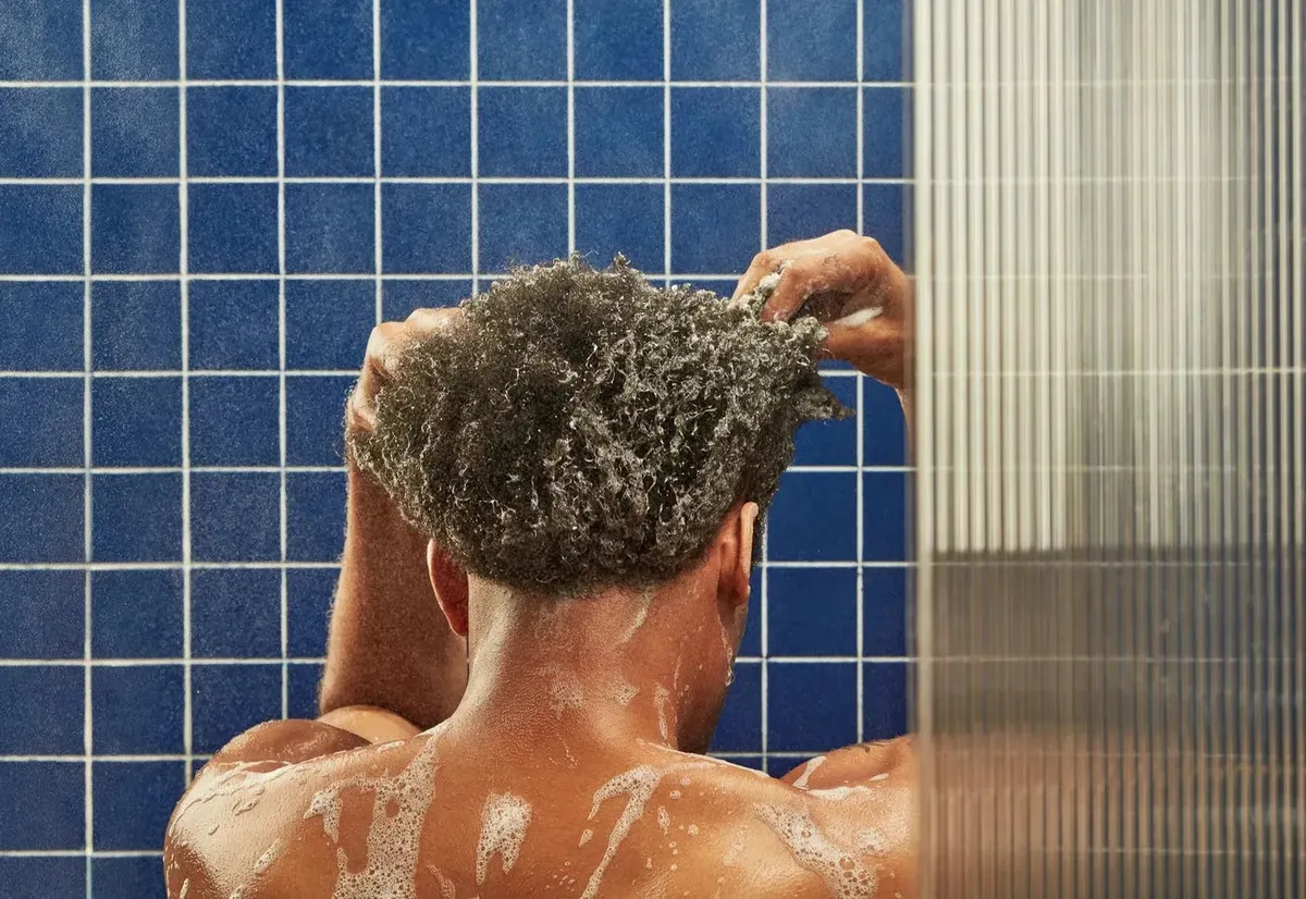 Washing hair with Flakes in a blue-tiled shower